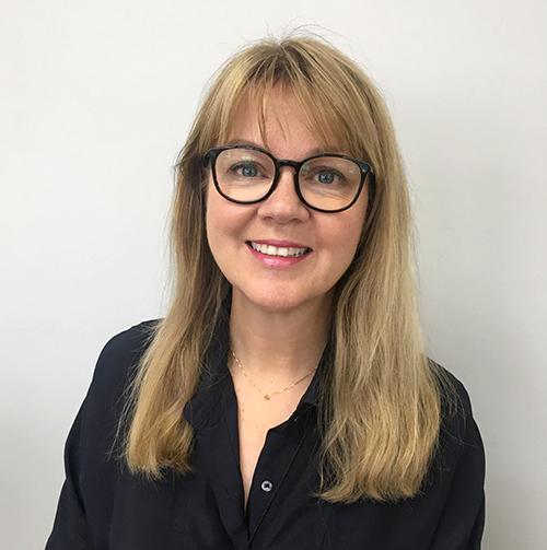 a woman wearing glasses and smiling at the camera