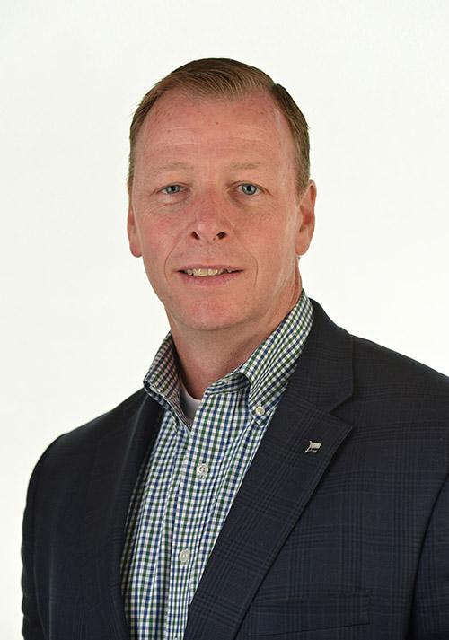 a man wearing a suit and tie smiling at the camera