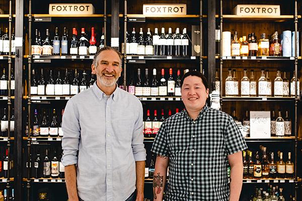 a man standing next to a bottle of wine in front of a store