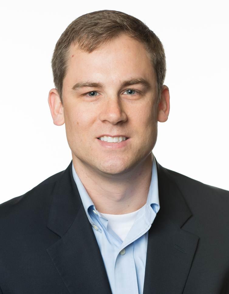 a man wearing a suit and tie smiling at the camera