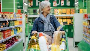 Woman shopping pushing a full grocery cart