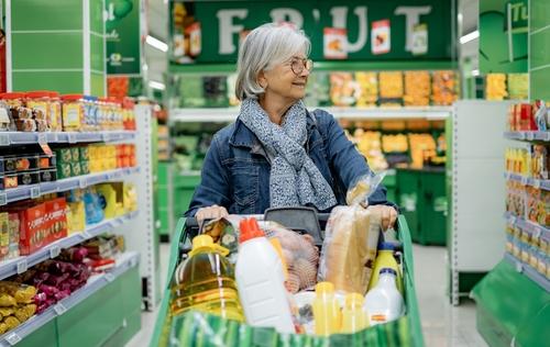 Woman shopping pushing a full grocery cart